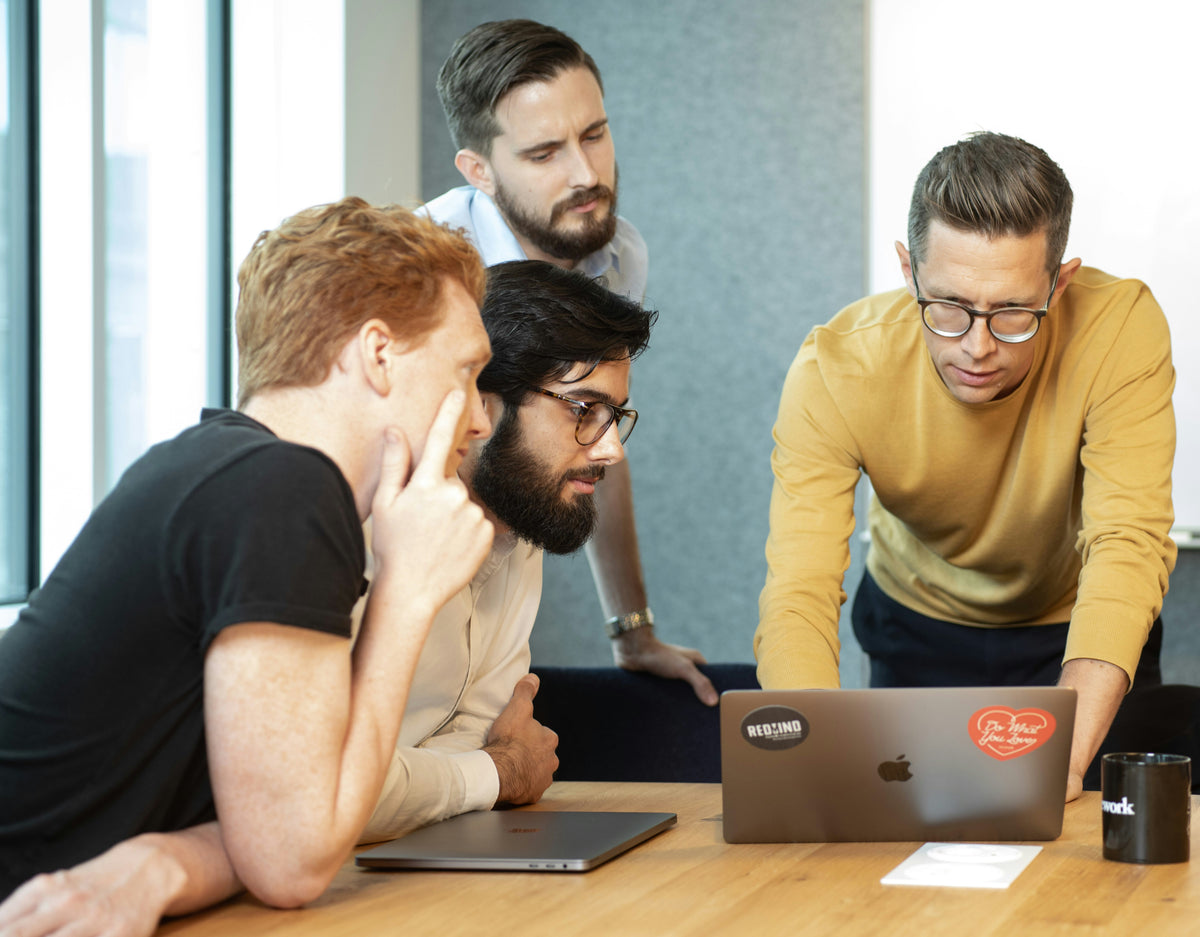Group of professionals analyzing data on a laptop, focused on market research and paid research studies.